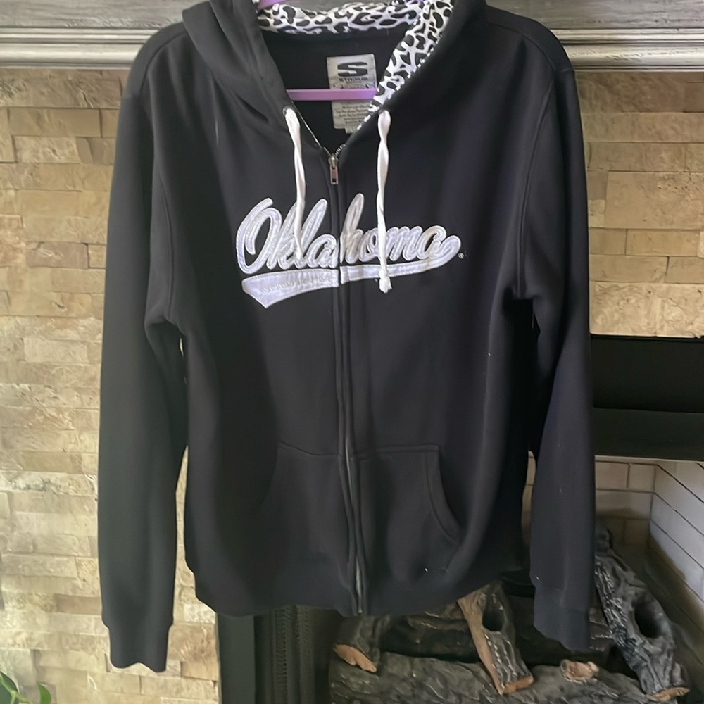 Black Oklahoma zip up hoodie with white and silver lettering.